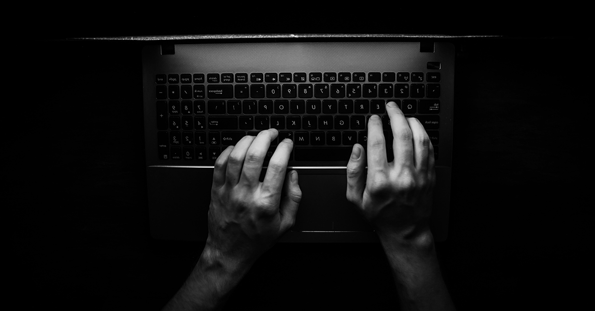 Hands typing keys on laptop